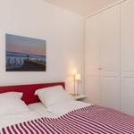 Schlafzimmer mit rotem Bett, weißen Wänden und Kleiderschrank.