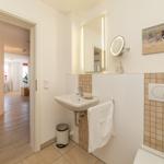 Badezimmer mit Waschbecken, Spiegel und Wandbildern.