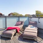Dachterrasse mit zwei Liegestühlen und Blick auf die Stadt