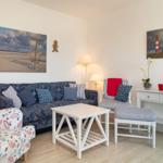 Wohnzimmer mit Sofa, Stühlen und Wandbildern