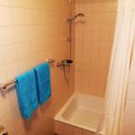 Bad mit Dusche, Badewanne und blauen Handtüchern.