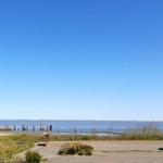 Parkplatz mit Blick aufs Wasser und einen roten Gebäudeblock.