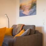 Ein grauer Sofa mit Kissen und Decke unter einem Wandbild.