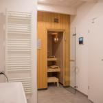 Dusche mit Glaswand, Sauna mit Holzverkleidung und Duschbereich mit Heizkörper.