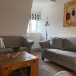 Zwei Sofas, Holztisch, Wandbild und Fenster mit Rollladen.