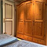 Schlafzimmer mit Holzschrank und Bett mit kariertem Bettzeug.