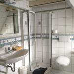 Badezimmer mit Dusche, Waschbecken und WC. Wandfliesen mit Meeresmotiven.