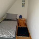 Ein Schlafzimmer mit Dachschräge, Bett, Nachttisch und Teppich.
