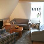 Wohnzimmer mit Sofa, Sessel und Holztisch. Fenster mit Jalousie und Wandbild.
