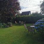 Garten mit zwei Tischen, Stühlen, Blumen und einem Blick auf ein Haus.