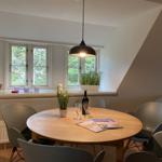 Rundes Esszimmer mit Tisch, Stühlen und Fensterblick auf Grün.