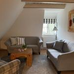 Wohnzimmer mit zwei Sofas, Holztisch und Fenster mit Rollladen.