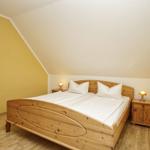 Schlafzimmer mit Holzbett, Nachttischen und gelber Wand.