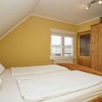 Schlafzimmer mit Dachschräge, Holzbett und Kleiderschrank