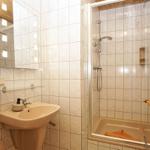 Bad mit Dusche, Waschbecken und Spiegel an der Wand