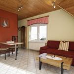 Wohn- und Essbereich mit Sofa, Tisch, Fenster und Holzdecke.