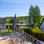 Terrasse mit Tisch und Stühlen, Blick auf Hütten und Hafen.