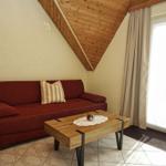 Ein Wohnzimmer mit rotem Sofa, Holztisch und schrägen Holzwänden.