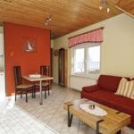 Wohnbereich mit Sofa, Tisch und Küchenzeile unter Holzdecke.