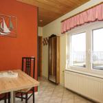 Esszimmer mit Tisch, Stühlen und Fenster mit Vorhängen.