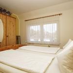 Schlafzimmer mit Holzbett, Kleiderschrank und Fenster mit Vorhängen.