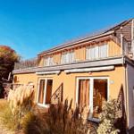 Zweistöckiges Haus mit Balkon und螺旋楼梯. Garten mit Gras und Pflanzen.