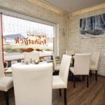 Esszimmer mit weißen Stühlen, Holzboden und Wandbild mit Segelyacht.