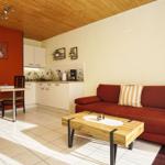 Wohnküche mit rotem Sofa, Holztisch und Küchenzeile.