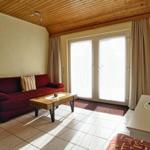 Wohnzimmer mit Sofa, Couchtisch und TV. Fenster mit Vorhängen.