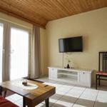 Wohnzimmer mit TV, Tisch, Stuhl und Fenster zur Außenseite.