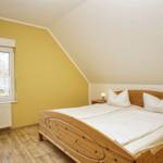 Schlafzimmer mit Holzbett, Fenster und Holzfußboden