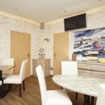 Raum mit zwei Tischen, Wandbildern und Fernseher an der Wand.