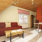 Wohn- und Essbereich mit Sofa, Tisch und Stühlen unter Holzdecke.