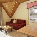 Ein Wohnzimmer mit rotem Sofa, Holztisch und Holzdach.