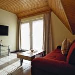 Wohnzimmer mit rotem Sofa, Fernseher und Fenster mit Vorhängen.