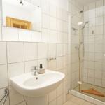 Badezimmer mit Dusche, Waschbecken und Spiegel