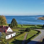 Haus mit Blick auf See, Grünanlagen und gepflasterte Wege.