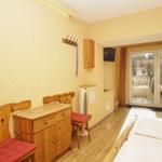 Zimmer mit Holzmöbeln, Bett und Glastür zum Balkon.