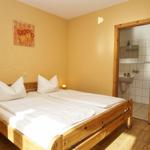 Zimmer mit Holzbett, Wandbild und Blick in Bad