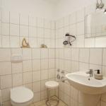 Badezimmer mit Toilette, Waschbecken und Spiegel an der Wand.