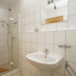 Badezimmer mit Dusche, Waschbecken und Spiegel