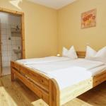 Schlafzimmer mit Holzbett, Nachttisch und Tür zum Badezimmer.