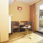 Zimmer mit Sitzbereich, Schlafplatz und Glastür zum Balkon.