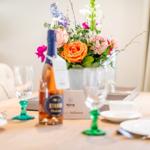 Tisch mit Blumen, Weinflasche und Geschirr