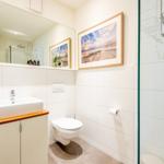 Badezimmer mit Dusche, Toilette und Waschbecken mit Spiegel