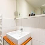 Badezimmer mit Waschbecken auf Holz, Spiegel und Heizkörper.