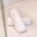 Zwei weiße Handtücher liegen auf einer hellen Fläche.