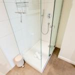 Dusche mit Glaswand, Handbrause und Handtuch