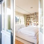 Schlafzimmer mit weißem Bett und Bücherregal an der Wand.