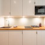 Küche mit Holzplatte, Spüle, Herd und Mikrowelle.